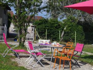 a table with colorful chairs and an umbrella at Les platanes in Aignes