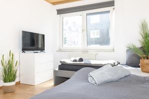 a bedroom with two beds and a tv and a window at CosyHomes24 - Centrally with balcony and parking space - GE09a in Gelsenkirchen