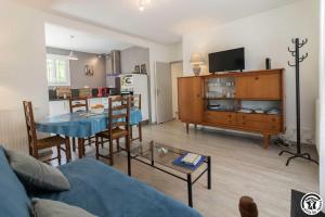 a living room with a blue table and a kitchen at Les lilas in Aussonne