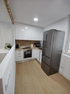 a kitchen with a stainless steel refrigerator and white cabinets at Apartamento La Ballena 2 - Las Huertas in Santoña