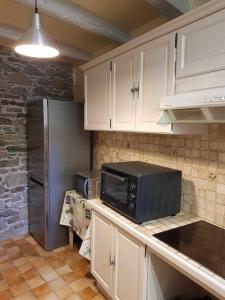 a kitchen with a microwave and a refrigerator at Le clos de bérande in Oô +9 photos