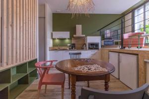 a kitchen with a wooden table and chairs in a kitchen at La grange des rampeaux in Saint-Lys