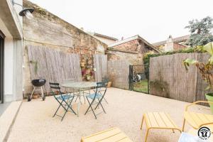 a patio with a table and chairs and a fence at La grange des rampeaux in Saint-Lys