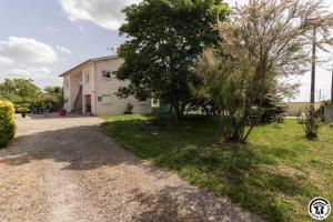 a house with a tree and a gravel driveway at Les hortensias in Aussonne