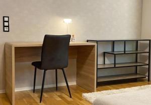 a desk with a black chair next to a shelf at zentrale Design-Ferienwohnung mit Balkon und Stellplatz in Karlsruhe - APOLONIAliving in Karlsruhe