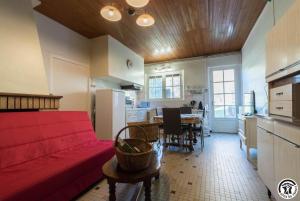 a living room with a red couch and a kitchen at Gîte les ecureuils in Montclar-de-Comminges