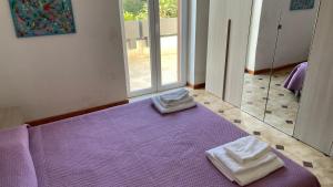 1 dormitorio con 1 cama morada y 2 toallas en Villetta Eliamare, en San Cataldo