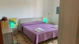 1 dormitorio con 1 cama morada y 2 toallas en Villetta Eliamare, en San Cataldo