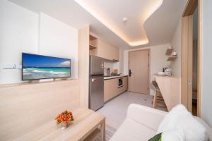 Sala de estar con cocina y TV en la pared en 全新现代风格 魅力泳池公寓, en Kamala Beach