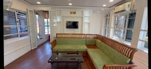 a living room with a green couch and a tv at Marari Xavier's Inn in Alleppey