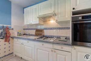a kitchen with white cabinets and a stove top oven at Le clos bleu in Gauré
