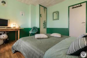 a bedroom with green walls and a bed with two pillows at Comà a l'ostal in Montégut-Lauragais