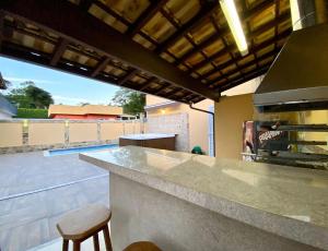 una cucina con un bancone e un bar con uno sgabello da bar di Casa Jacuzzi Piscina Churrasqueira 10 min Itaipava a Inglesa