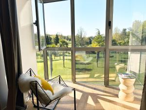 a room with a large window with a view of a yard at Le Golf Comme Jardin Dormez au Cœur du Parcours in Lésigny