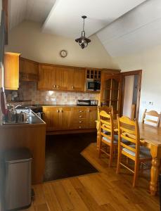 a kitchen with wooden cabinets and a table and chairs at Yewwood Cottage in Newry