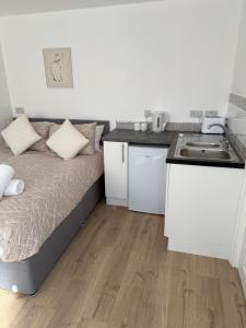a small room with a bed and a kitchen at Colne cabin in Earls Colne