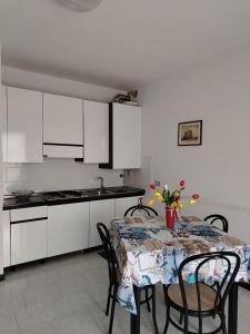 a kitchen with a table with chairs and white cabinets at Appartamenti Fiordaliso in Sirmione