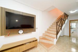 a living room with a large television and a staircase at 4-Bed Villa Sleeps 8 Pets Ok & 10 min to Beach in Los Alcázares
