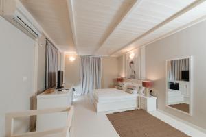 a white living room with a couch and a tv at Soleil Village & Villas in Jal