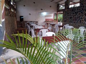 库里蒂Curitagua Hotel Campestre的一间设有白色桌椅的餐厅,