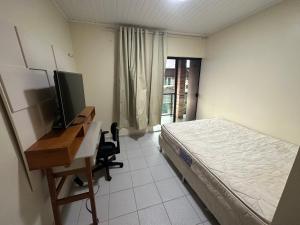 a bedroom with a bed and a desk with a computer at Hospedaria HAPPY in Salinópolis