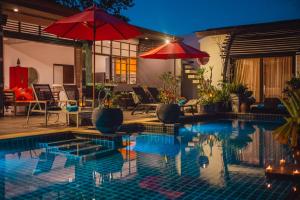 una piscina con 2 sombrillas y una casa en Chalong Sunset Villa, en Chalong  10 fotos más