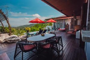 un patio con una mesa con sillas y una sombrilla en Chalong Sunset Villa, en Chalong 