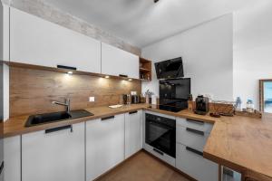 a kitchen with white cabinets and a wooden counter top at Appartment hypercentre Evian in Évian-les-Bains +8 photos