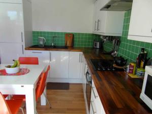 a kitchen with white cabinets and green tiles at Modern and stylish flat in London