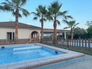 a swimming pool in front of a house with palm trees at Finca Laurel in Utrera