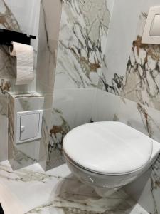 a white toilet in a bathroom with marble walls at Cozy Flat in Baia Mare