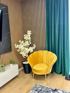 a yellow chair in a room with a plant at Cozy Flat in Baia Mare +8 photos