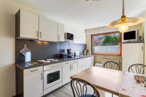 a kitchen with white cabinets and a dining table at Riedel Fronz in Lennestadt +16 photos