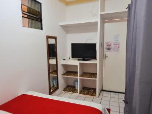 a room with a tv on a shelf with a mirror at São Luís Hostel - Dormitórios Compartilhados e Quartos Privativos in São Luís