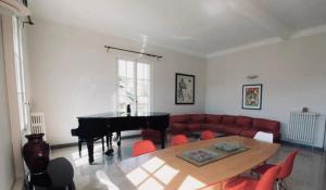 ein Wohnzimmer mit einem Tisch und einem Klavier in der Unterkunft Villa prestigieuse avec piscine privée au cœur de Nice in Nizza
