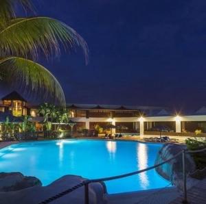 a large blue swimming pool at night at Le Nid d'Amour Créole - Studio romantique avec accès au lagon et à la piscine XXL de 1 000 m2 - Saint-François in Saint-François