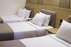 three beds in a hotel room with white pillows at Delmar Hotel Matrouh in Marsa Matruh