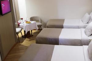 a hotel room with two beds and a small table with a table at Delmar Hotel Matrouh in Marsa Matruh