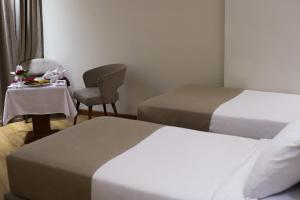 a room with two beds and a table and a chair at Delmar Hotel Matrouh in Marsa Matruh
