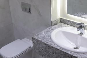 a white bathroom with a sink and a toilet at Delmar Hotel Matrouh in Marsa Matruh