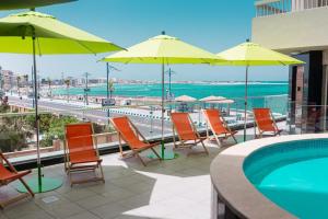 a group of chairs and umbrellas next to a swimming pool at Delmar Hotel Matrouh in Marsa Matruh