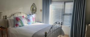 a bedroom with a white bed with pillows and a window at At the 5th in Langebaan