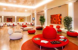 Residence Modus Vivendi في سانريمو: غرفة كبيرة بها كراسي وطاولات حمراء وبيضاء