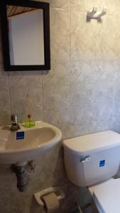 a bathroom with a white toilet and a sink at Hospedaje Las Cabañas in Monguí +45 photos