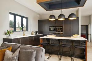 a kitchen with black cabinets and a kitchen island with bar stools at Holmer House Farm in Hereford