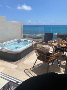 a hot tub on a patio with a table and chairs at cala luna spa vue mer , clim, à 50m de la plage , literie luxe , entièrement équipé in Conca