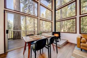 una sala da pranzo con tavolo, sedie e ampie finestre di Glass Cabin Under the Pines | Hot Tub • Seclusion a Willow Valley