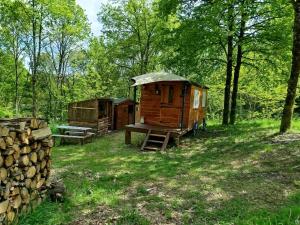 two out houses in the woods with a picnic table at Roulotte et Cabane Par Hasard in Saint-Bressou