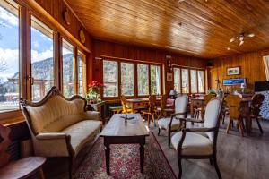 a living room with chairs and tables and windows at Hotel Le Campagnol in Champoluc
