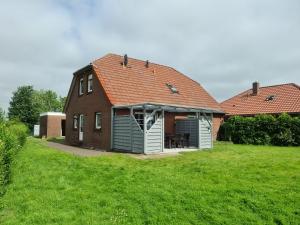 a house with a red roof on a green field at Ferienhaus vor den Toren Greetsiels in Krummhörn